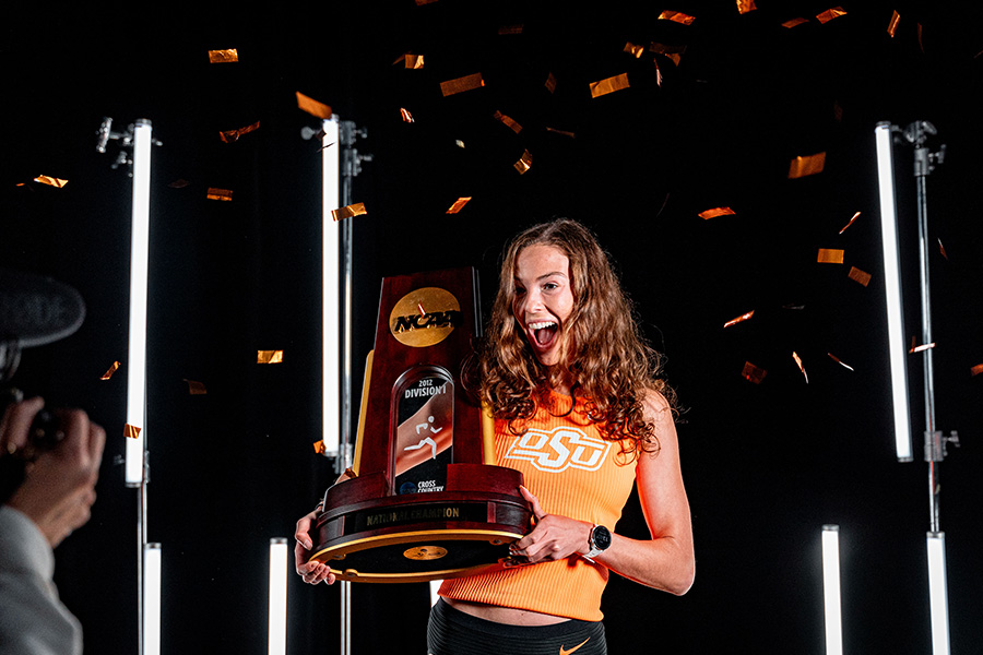 A woman stands excitedly with a trophy for a photo. A woman stands excitedly with a trophy for a photo.