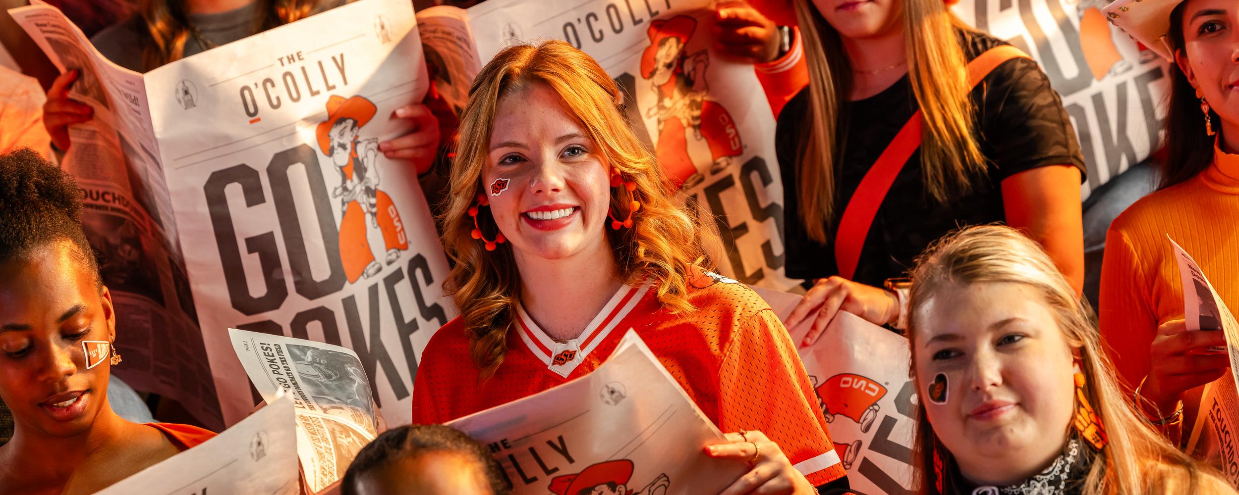 Students on bleachers at basketball game ready to cheer on Cowboys