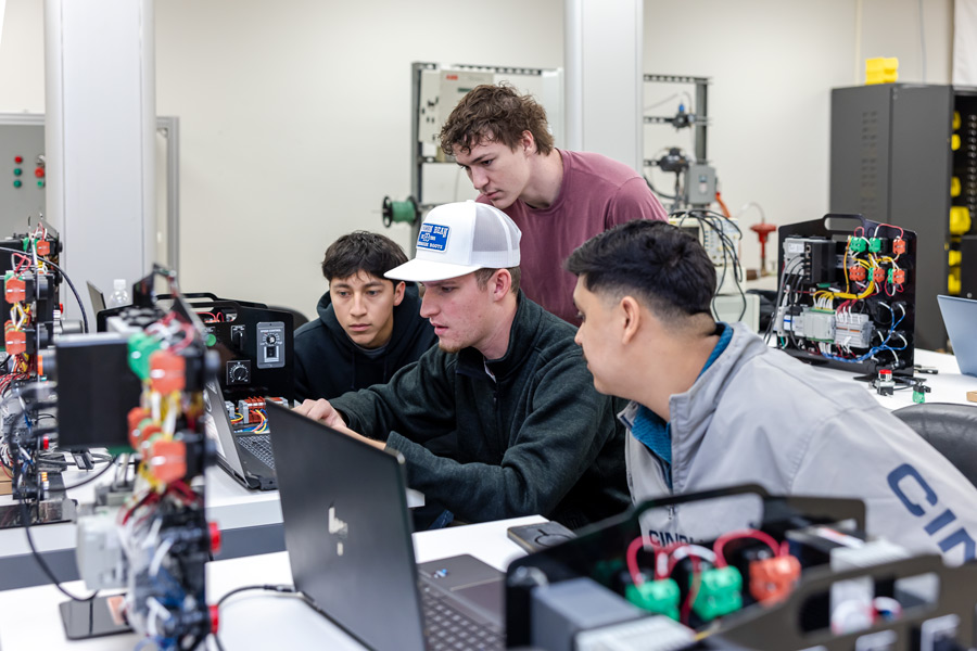 Students gather around computer in a classroom setting